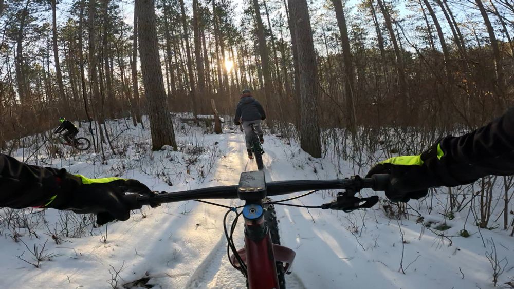 Following two people riding bikes on the snow