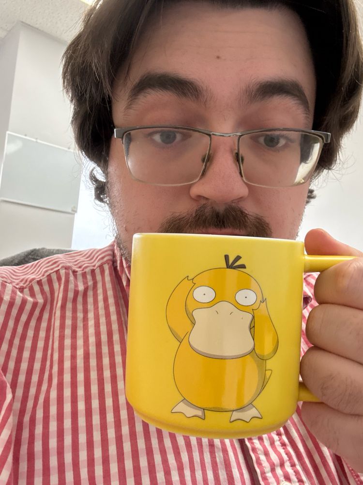 Silly man in a bestriped shirt holds a very yellow mug featuring psyduck