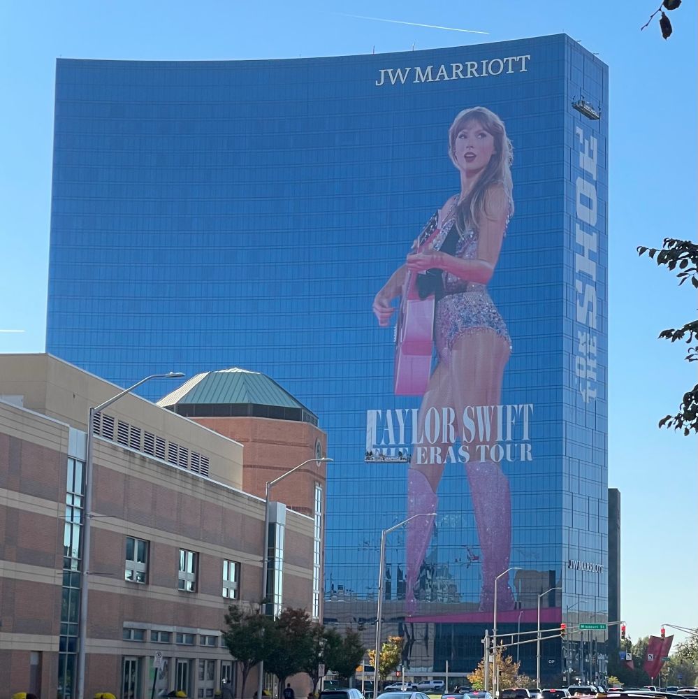 A gigantic picture of Taylor Swift in her Eras Tour opening costume holding her guitar screened onto JW Marriott hotel in Indianapolis. 