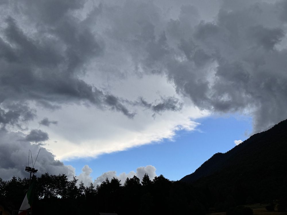 Uno sprazzo di cielo azzurro tra le montagne e le nuvole minacciose che sopraggiungono. In arrivo un temporale 