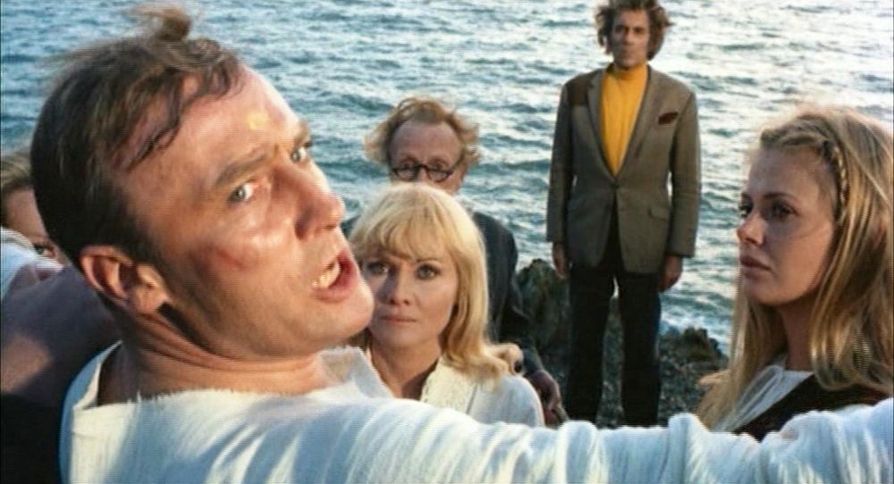 Sergeant Howie dressed in ritual gear shouting while Lord Summerisle and the villagers look on