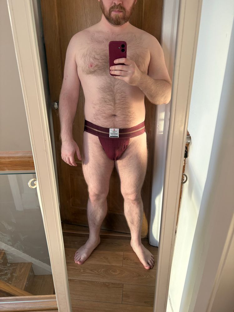 Me in front of a standalone mirror wearing a maroon wideband jockstrap