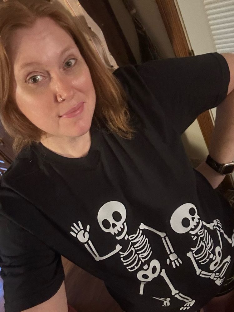 Me, a red head, wearing a black shirt with skeletons on it. In the rib bones the bones discreetly spell out Fuck Trump. 