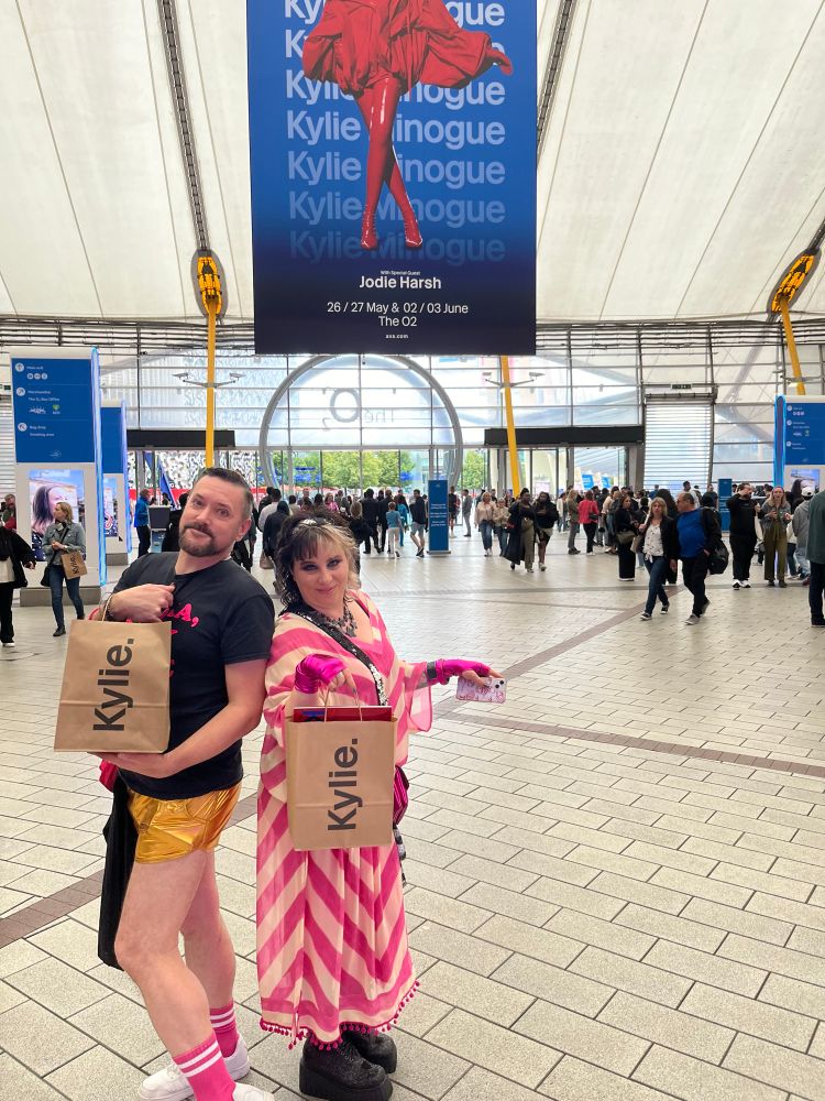 Me and my mate Jennie holding ‘Kylie’ bags in the O2 London with a Kylie Minogue poster hanging from the ceiling