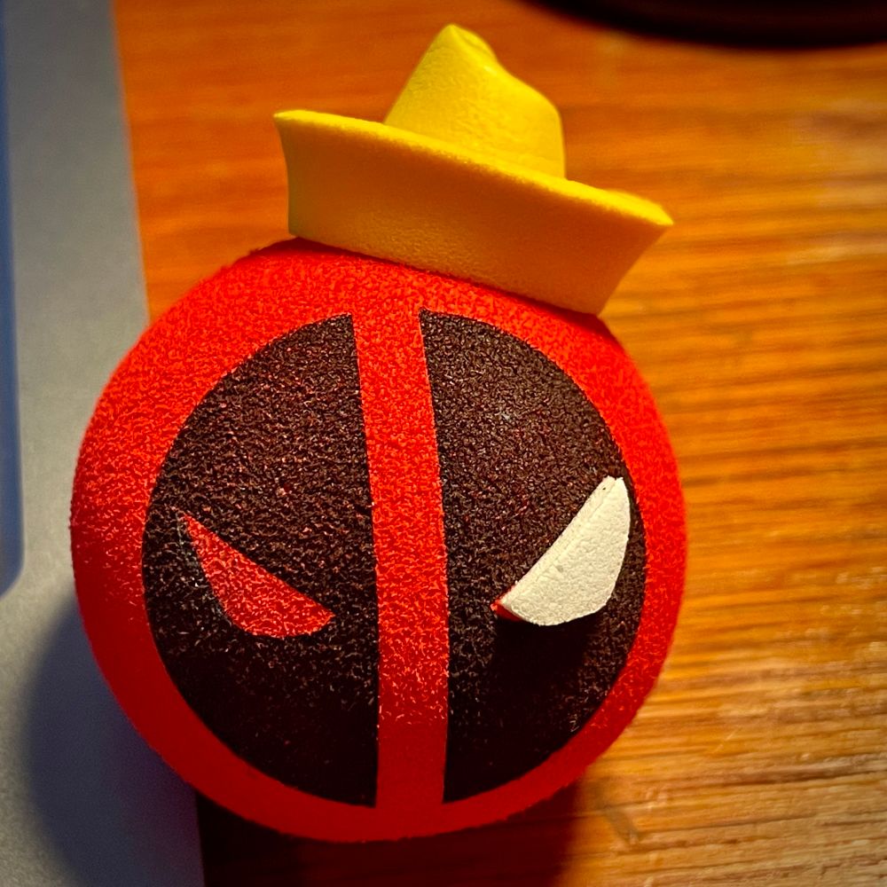 A close-up of a promotional Deadpool antenna ball, which is now missing an eye and has the top of its cap smooshed in.