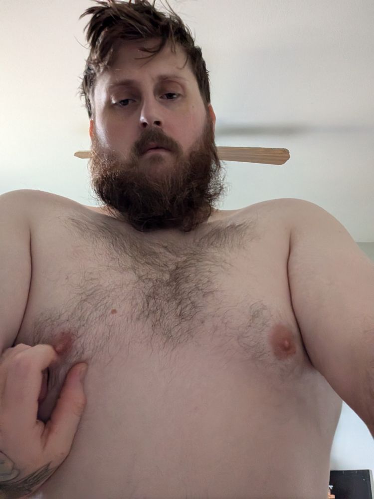 A dark haired, light skinned bare cheated bear. A lover hand caresses his nipple.