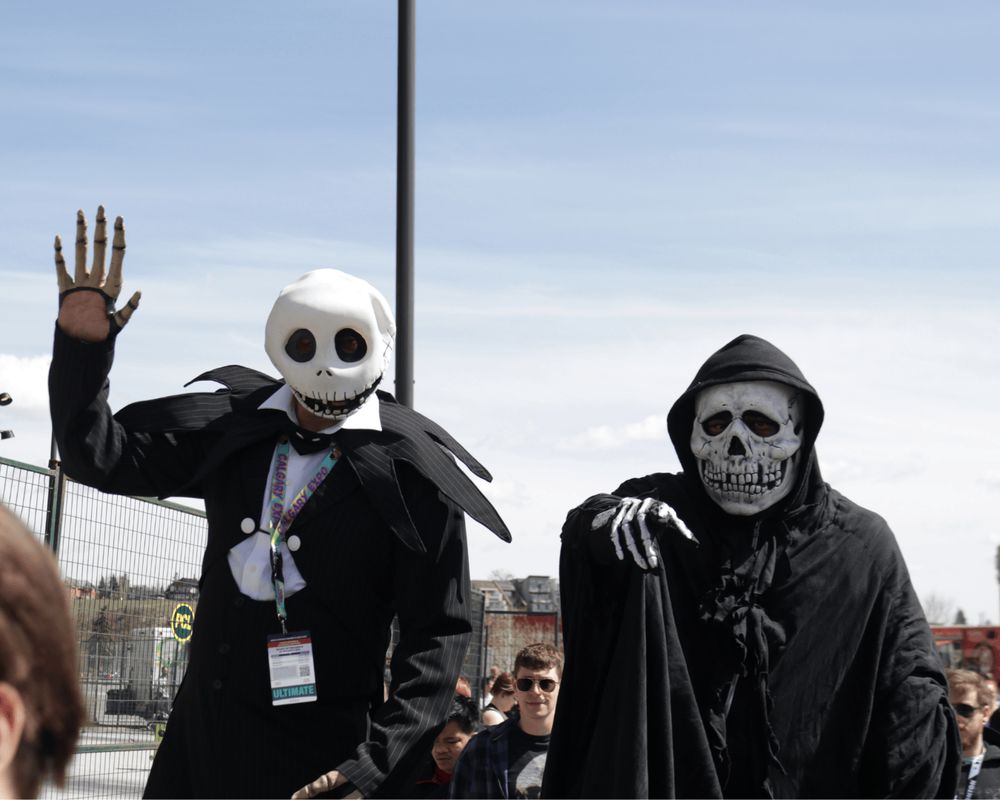 A Jack Skellington and Grim Reaper (both cosplayers) point and wave as their photo is taken.