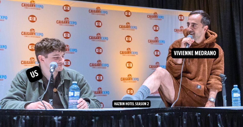 Blake Roman and Amir Talai of Hazbin Hotel on a stage with Amir's foot on the table. 