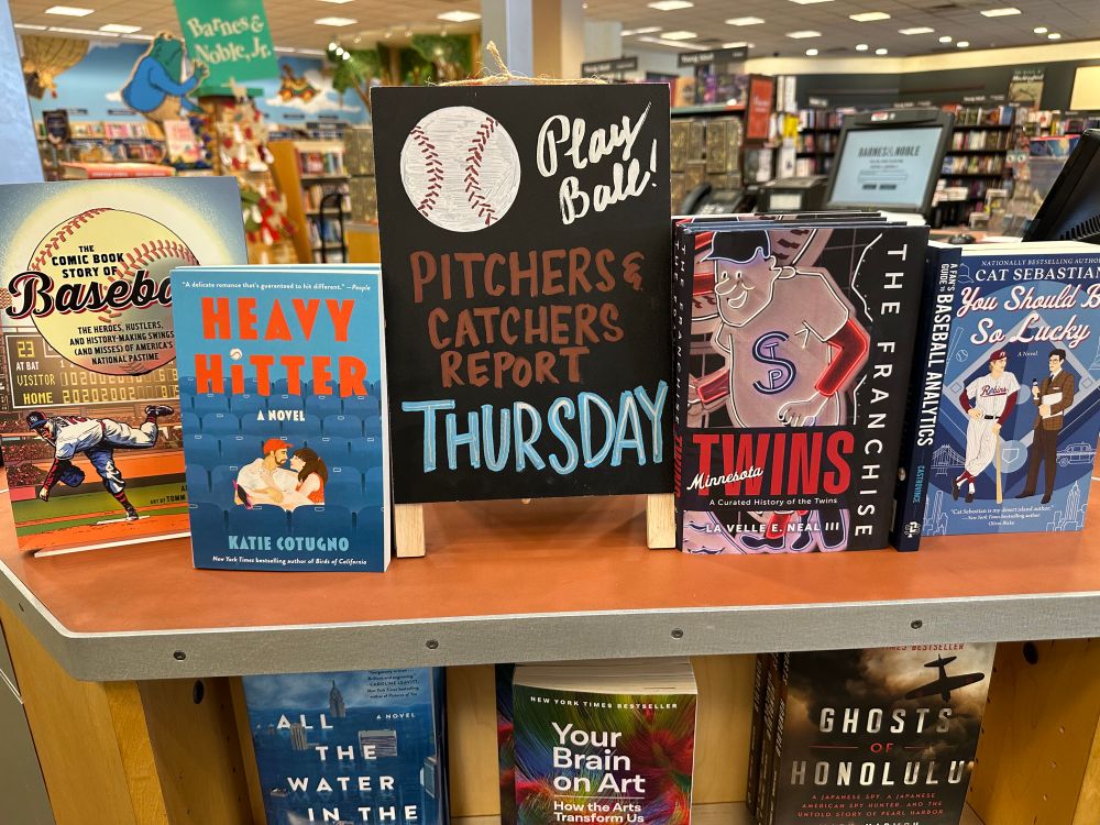 Barnes & Noble display with chalkboard sign announcing the date pitchers and catchers report to spring training, along with several baseball history books and novels.