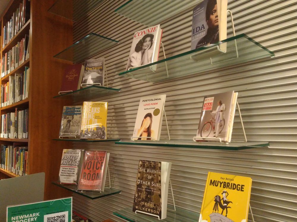 Library book display with books about newspapers, journalists, books of poems, and Muybridge by Guy Delisle