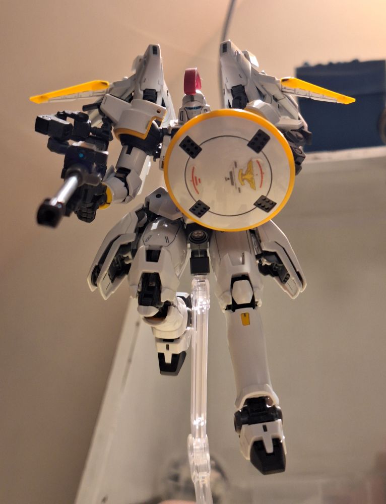 Real Grade Tallgeese, shot from below in a flying position, aiming it's canon downwards and defending itself with the shield