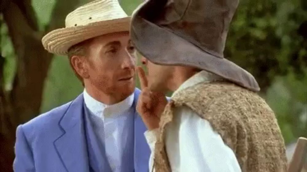 a man wearing a straw hat talks to another man