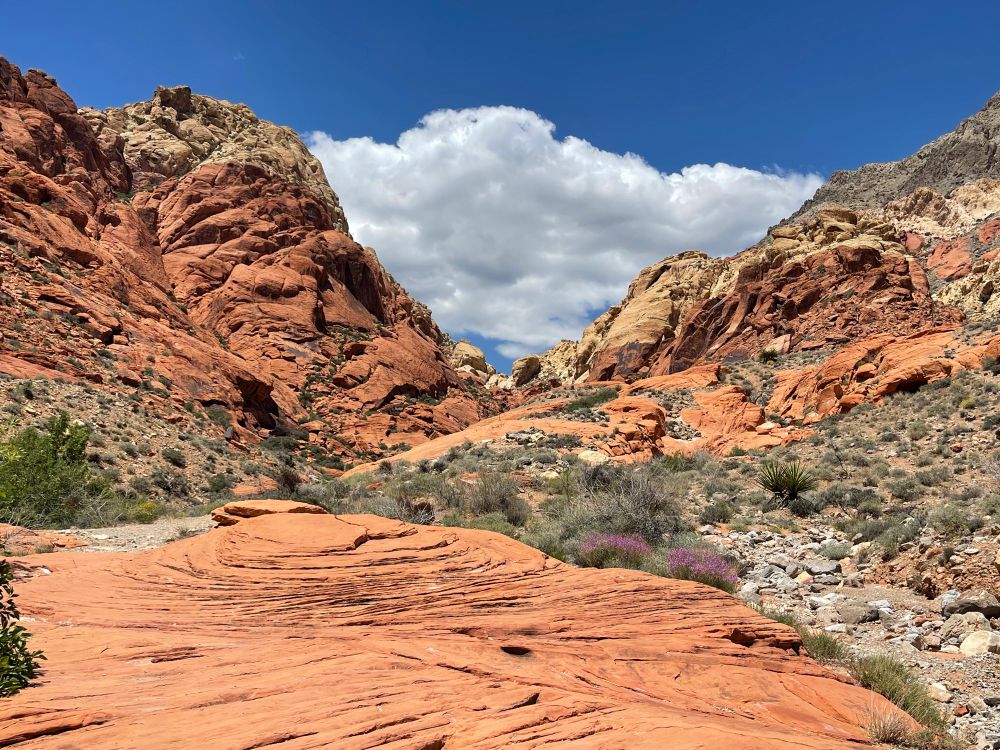 Red and white sandstone formations with clouds and blue sky above at Red Rock canyon in southern NV.