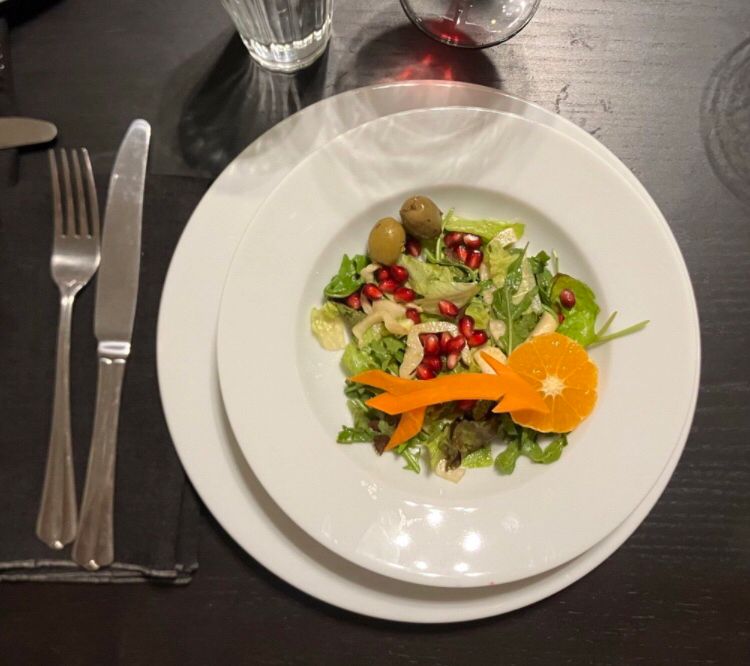 Salad topped with an arrow of carrot and hunters moon of tangerine 