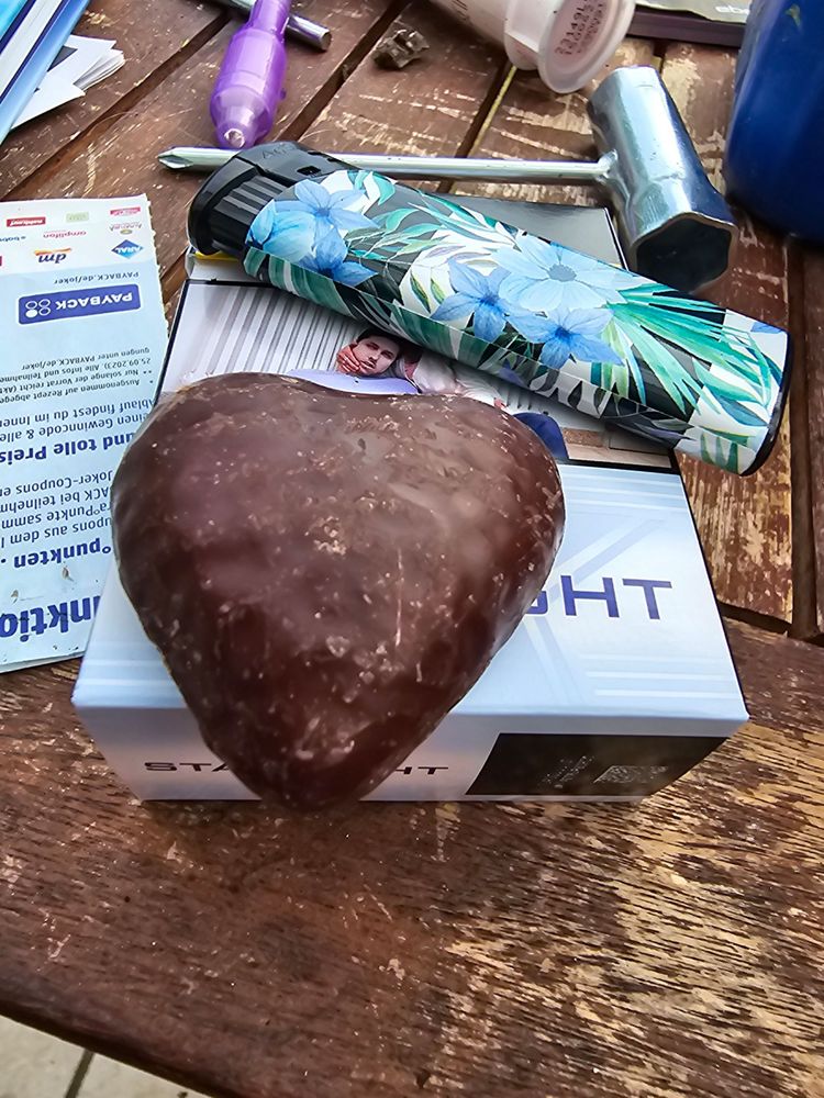 Eine Schachtel Zigaretten, auf der ein Feuerzeug und ein Lebkuchenherz liegt