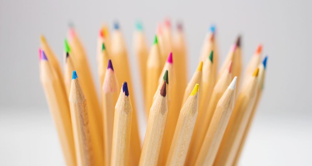 A stock photo of a collection of multi-coloured pencil crayons made of plain, pale carved wood.