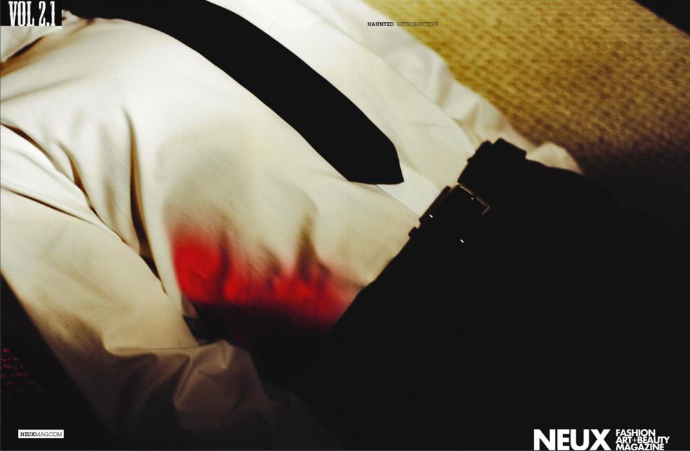 From the “Haunted” photo series by ©️ Vaunn Yevo. A man laying on the carpeted floor dressed in corporate attire with blood stained white shirt on his side. 