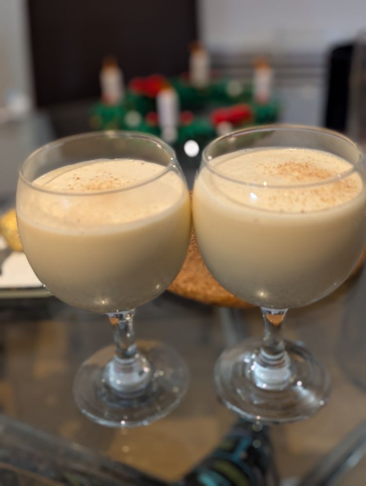 Two wine glasses of eggnog, with nutmeg on top. The fully lit LEGO Advent wreath is behind them.