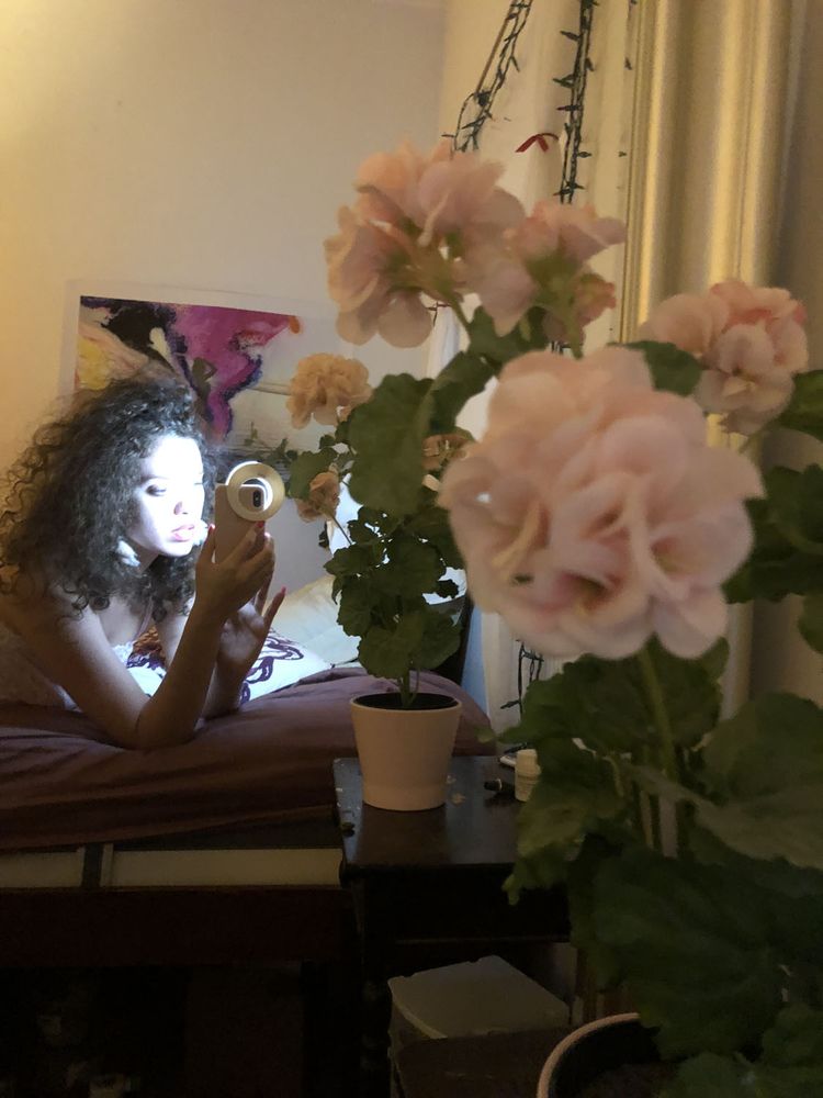 Image of model taking a flash selfie in front of flowers