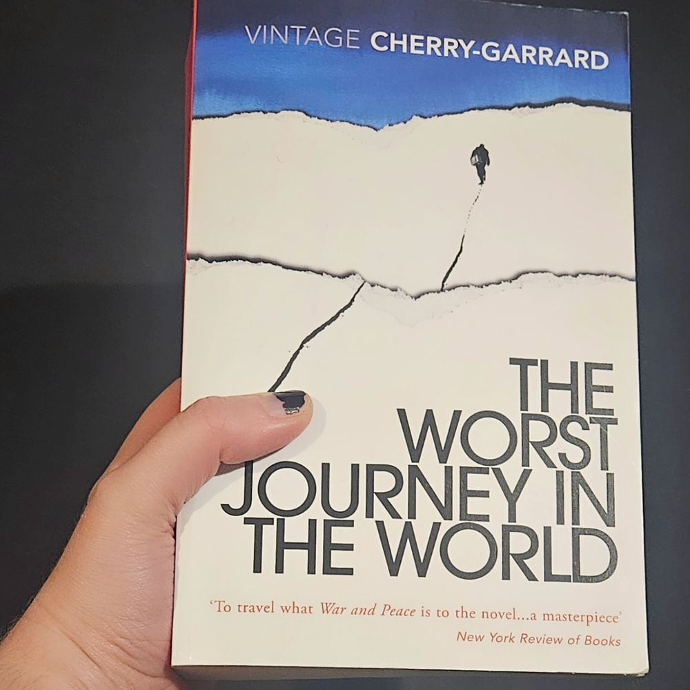 A stubby little hand holds up the Vintage edition of The Worst Journey in the World.