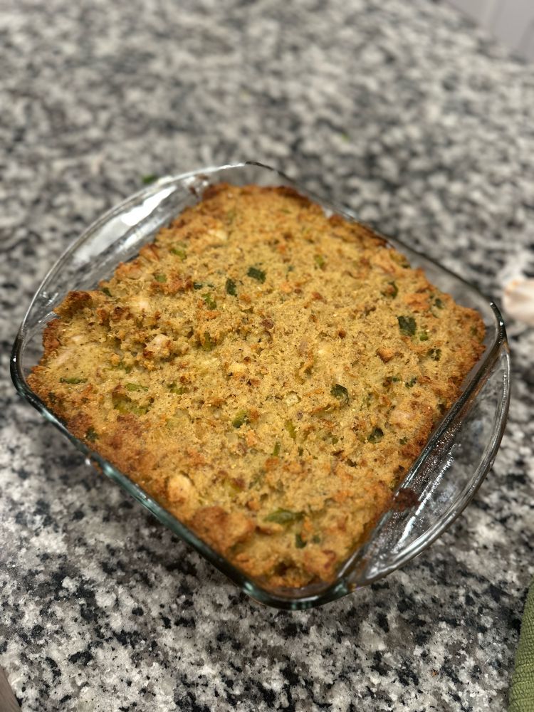 Clear baking pan sitting on a granite counter top with baked turkey dressing in it.