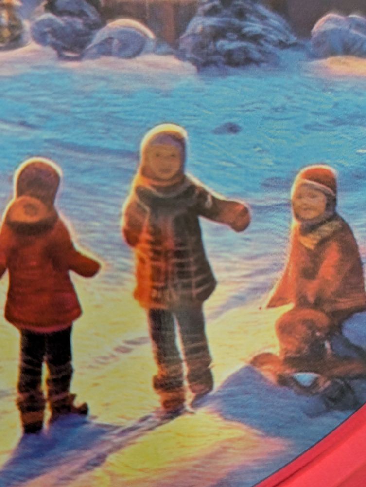 A close up on the children from the red cookie tin, where the middle child is seeming facing the viewer, but her feet and arms obviously extend outward as if her body was facing away from the viewer