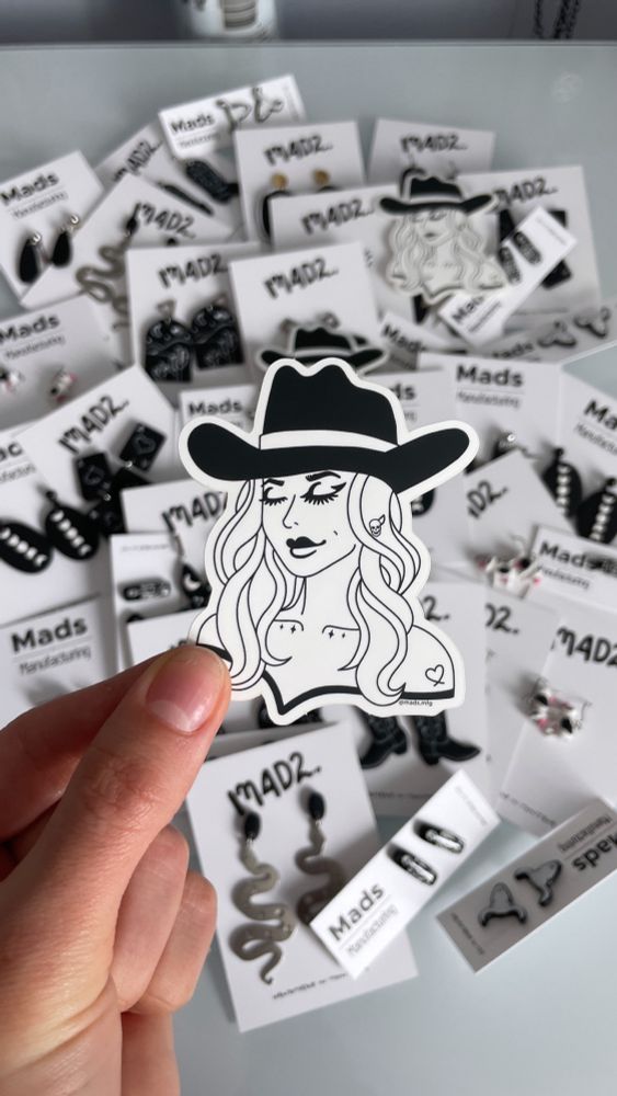 Black and white goth cowgirl stickers over background of earrings on cards 