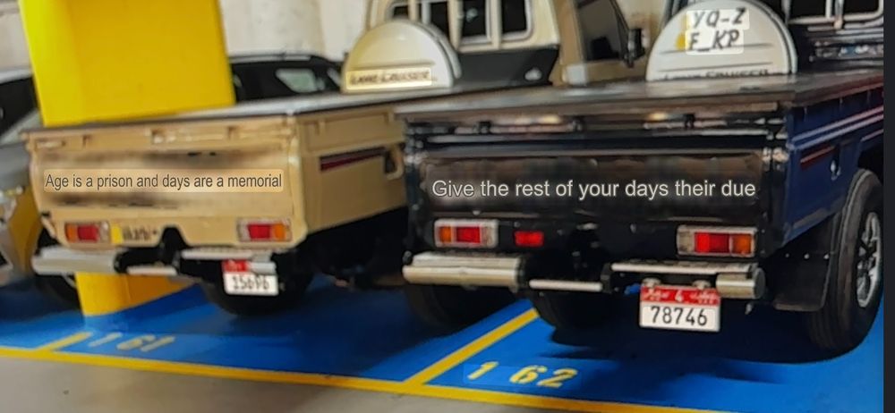 screenshot of google translate. picture of two trucks. truck on the left's Arabic inscription reads "Age is a prison and days are a memorial" and truck on the right reads "give the rest of your days their due." accuracy unknown.