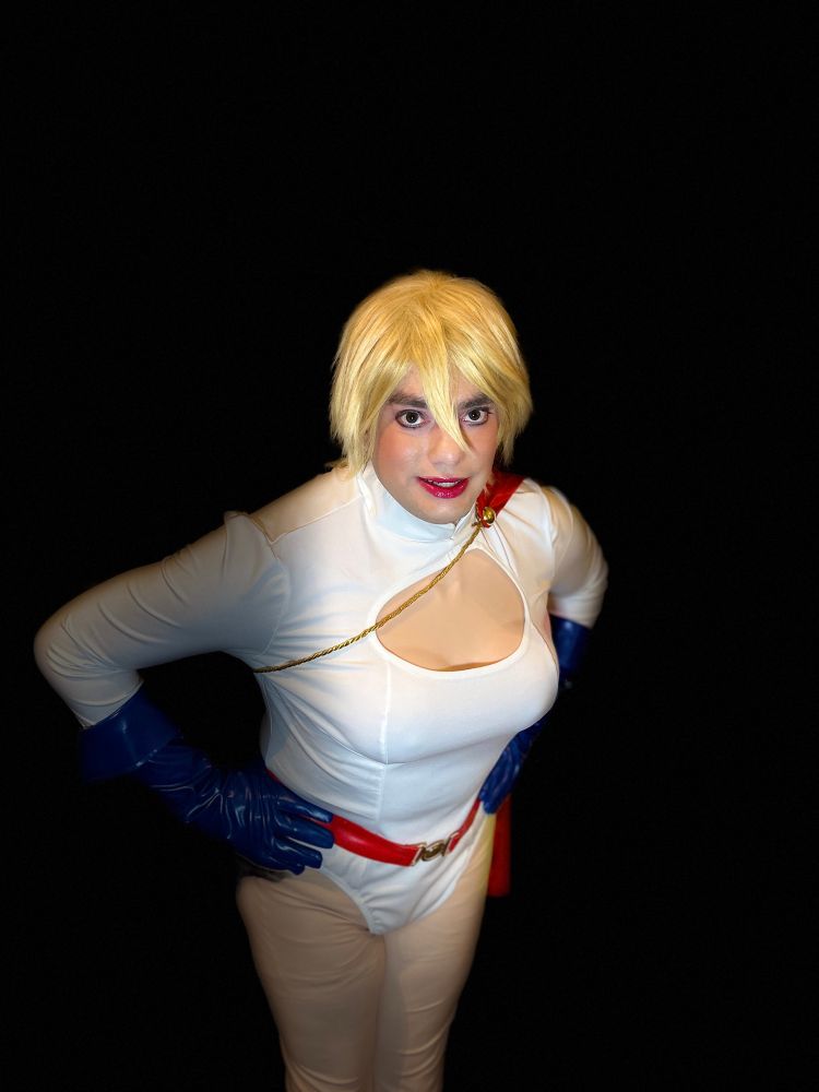 Me in my Power Girl cosplay smiling and leaning towards the camera with my hands on my hips.