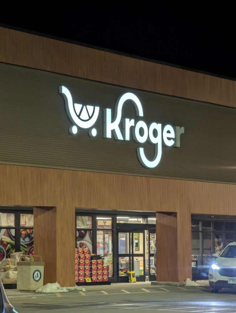 A backlit sign reading "Kroger." The second R is not lit, making the sign read "Kroge" which is similar to DOGE. Despite the caption Elon Musk has not taken over Kroger, as the store was staffed and well-stocked. Elon Musk is an unfrosted Pop-Tart of a person.