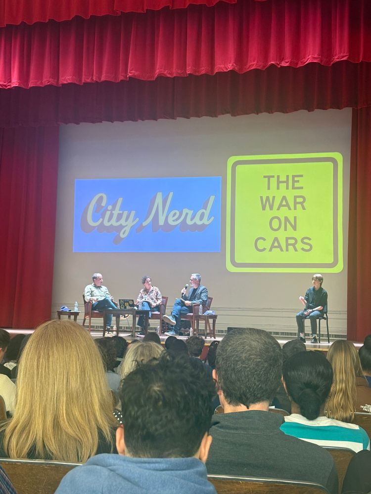 Nerd4cities(Ray) and the hosts of the war on cars on the stage of a packed event as they record a live podcast.