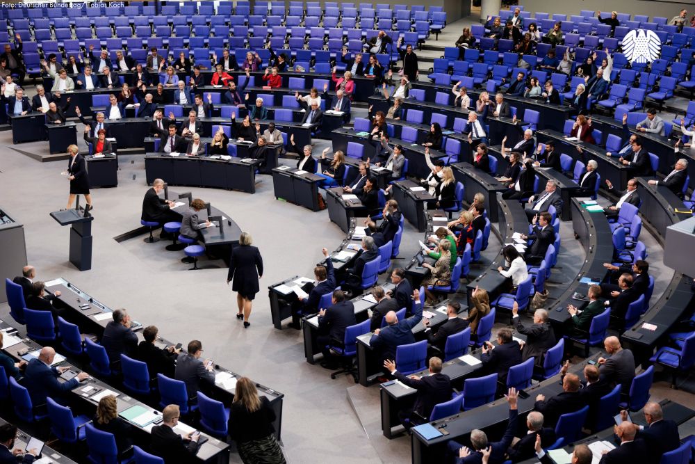 Zu sehen ist der Plenarsaal des Deutschen Bundestages. Die anwesenden Abgeordneten heben die Hand zur Abstimmung.