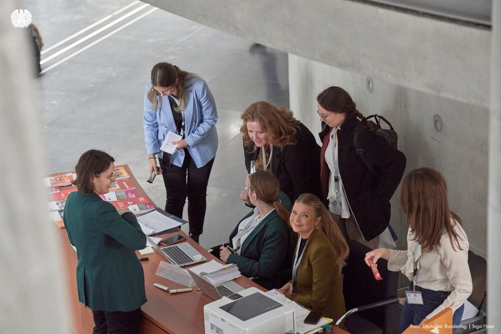 Teilnehmerinnen und Mitarbeiterinnen der Konferenz unterhalten sich am Infodesk.