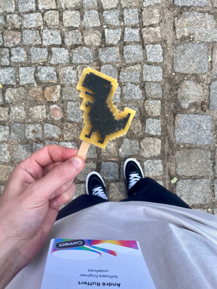 A hand holding a Google Chrome offline dinosaur ice cream popsicle.