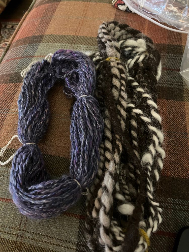 Two hanks of hand spun yarn. On the right, thick and irregular. The left much thinner and more regular 