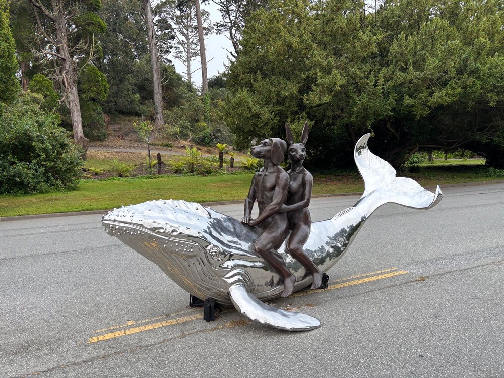 A statue in Golden Gate Park of a nude couple in pewter—one with a dog’s head and one with a rabbit’s head—riding on a chrome whale. 