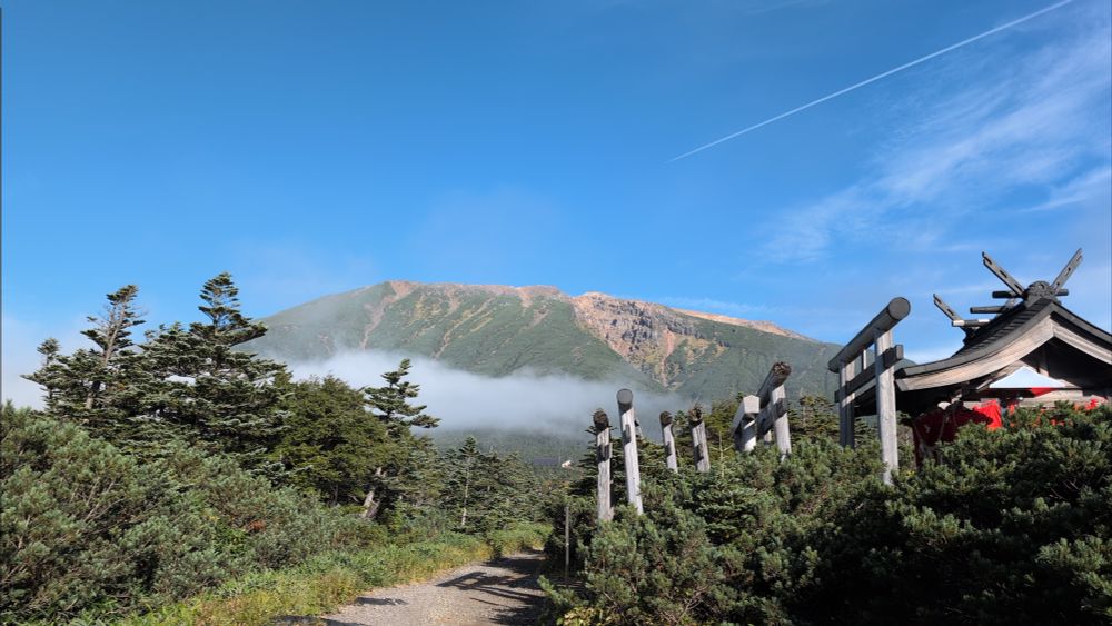 長野県王滝村の王滝登山口付近から見た御嶽山。
空は快晴。山体の中頃に薄い雲がかかっているのが見える。