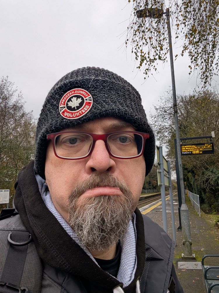 Man in black wooden hat and Canadian logo looking grumpy 