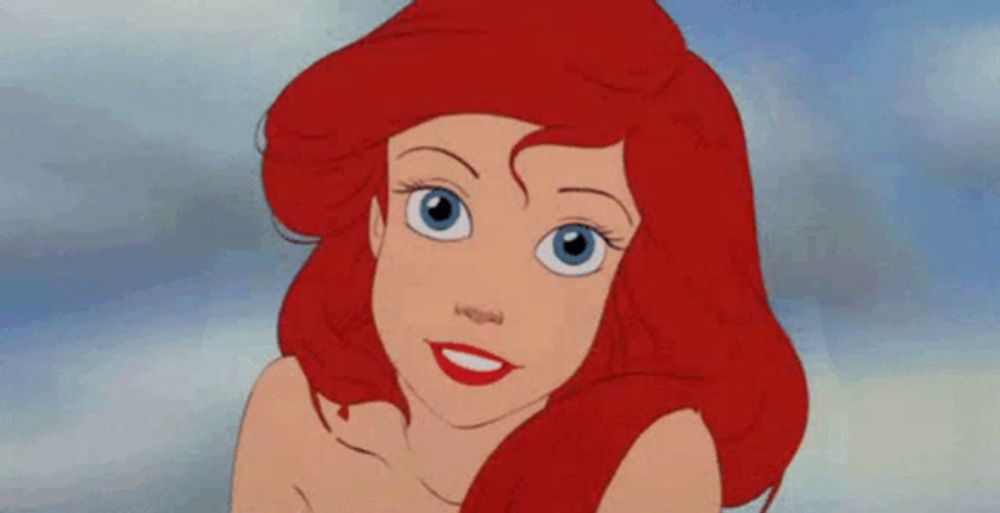 ariel from the little mermaid is smiling with red hair and blue eyes .