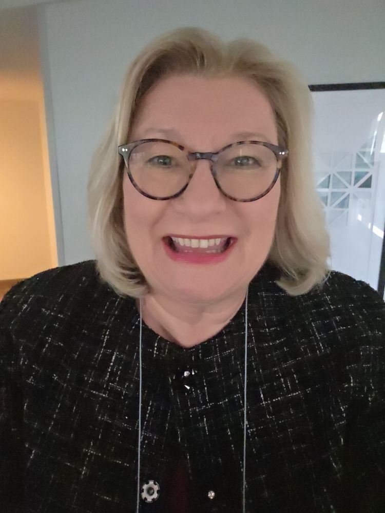 Smiling woman in dark jacket wearing glasses