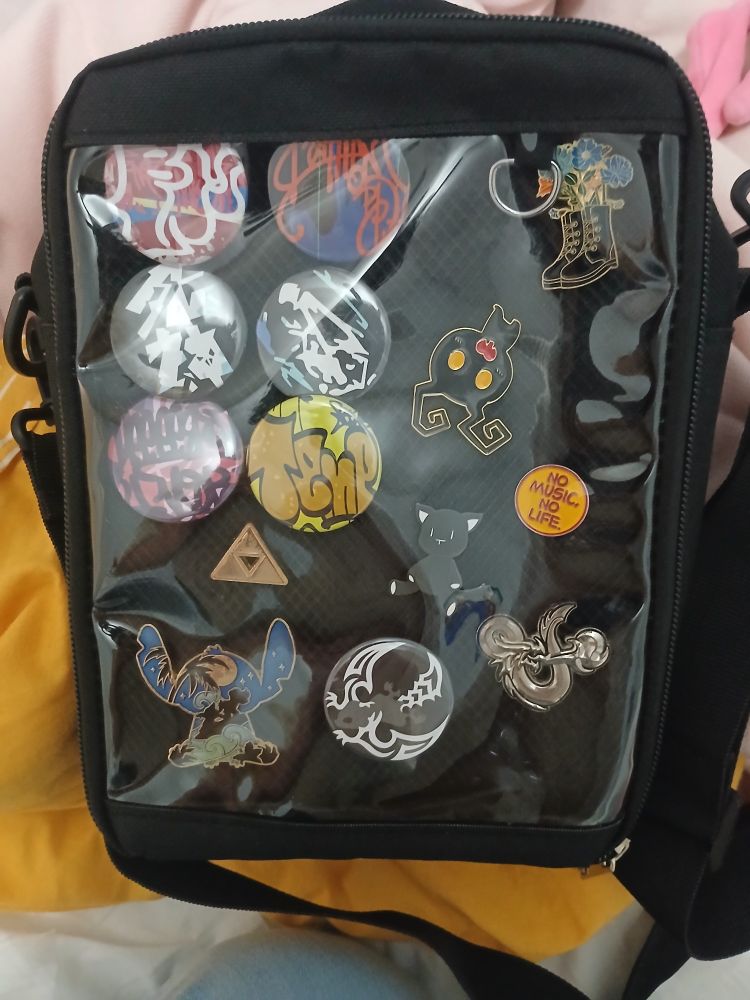 Six pins that are the darklit planet set from the game The World Ends With You, a Rhyme pin from the same game and Mr Mew, a Heartless pin from Kingdom Hearts holding a little heart, a D&D pin, TOWER RECORDS "No Music No Life" pin, Triforce pin from The Legend of Zelda, a pin of boots with flowers coming out of them, and a Stitch pin with Lilo and Stitch surfing beneath the stars within the silhouette.