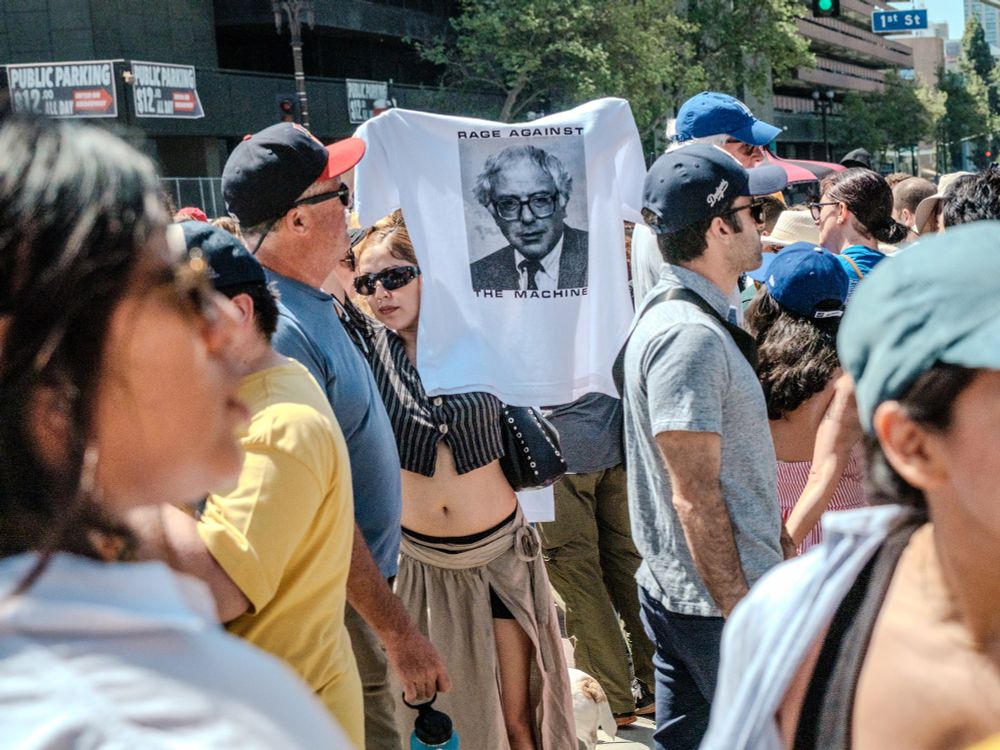 Woman holding up Bernie sanders rage against the machine shirt