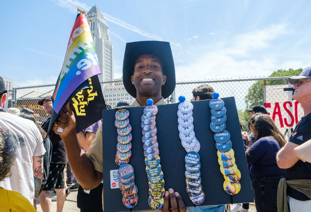 Man selling pins that say deport Elon and feminist af