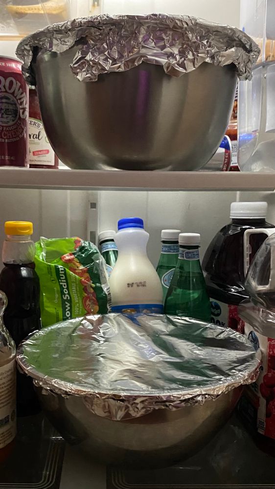 2 bowls in a fridge both topped with aluminum foil.