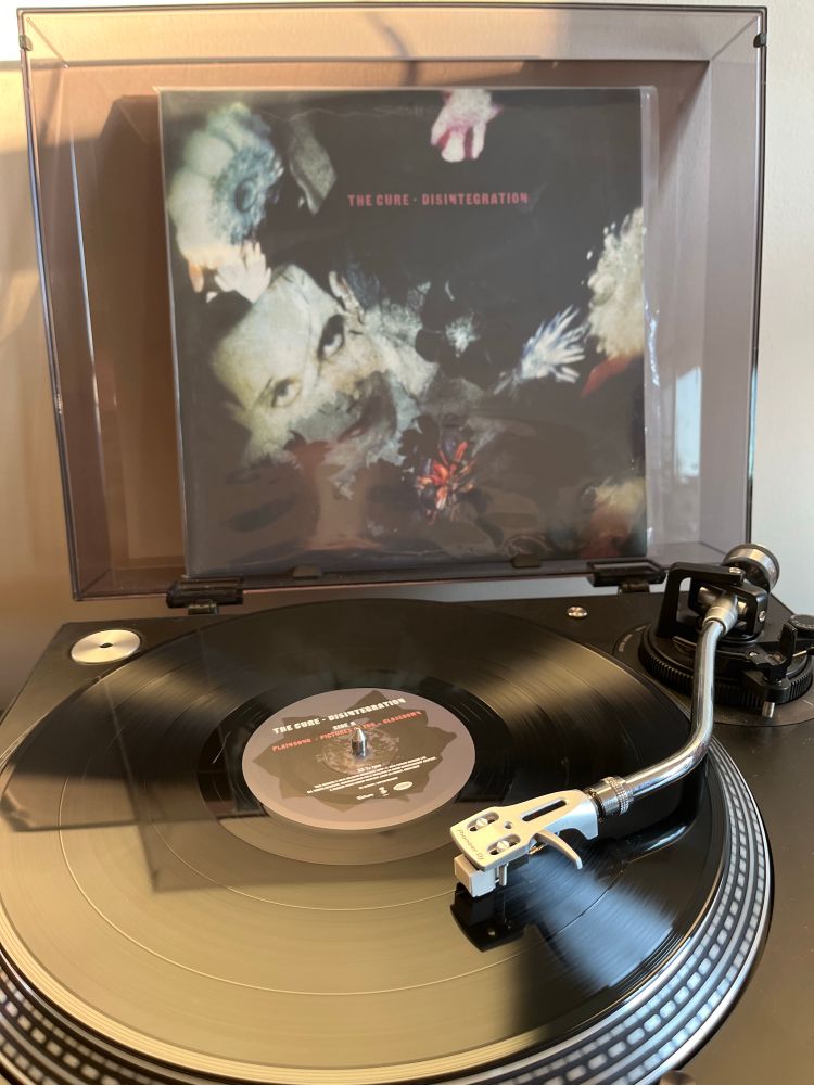 The Cure’s album “Disintegration” playing on my turntable. The album cover is mounted on the lid in the background with the vinyl platter spinning in the foreground.