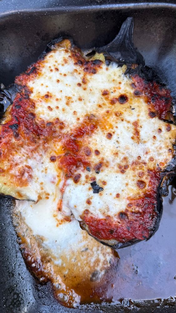 Charred aubergines sitting drenched in olive oil and pasta sauce, with nicely browned melted mozzarella draped over them.