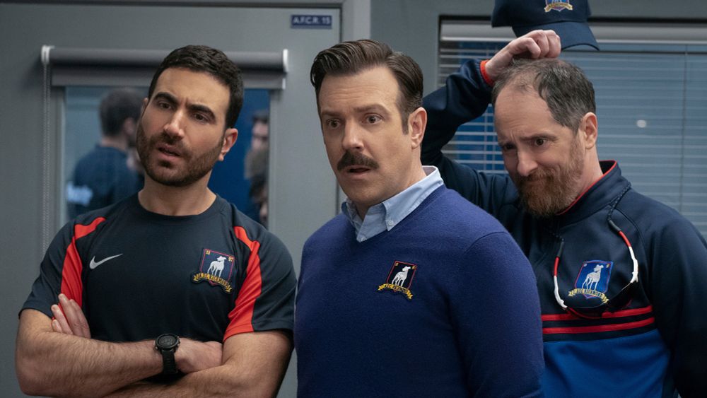 Screenshot from Ted lasso showing Roy, Ted, and Coach Beard looking confused and surprised.