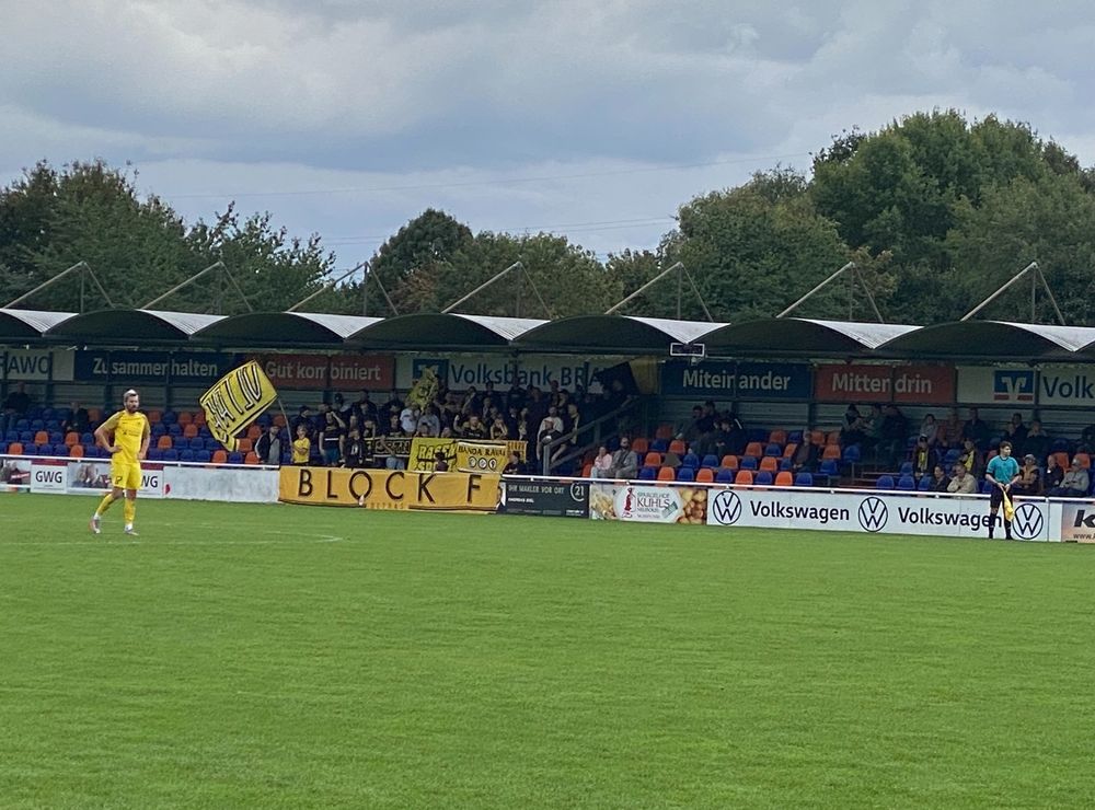 Tribüne mit Fans des SC Göttingen mit schwarz gelben Fahnen