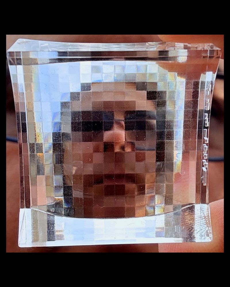 A person’s face viewed through a pixelated glass surface, causing a blocky distortion.