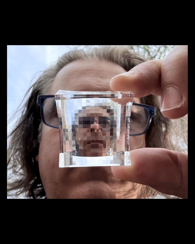 A distorted face seen through a pixelated glass block.